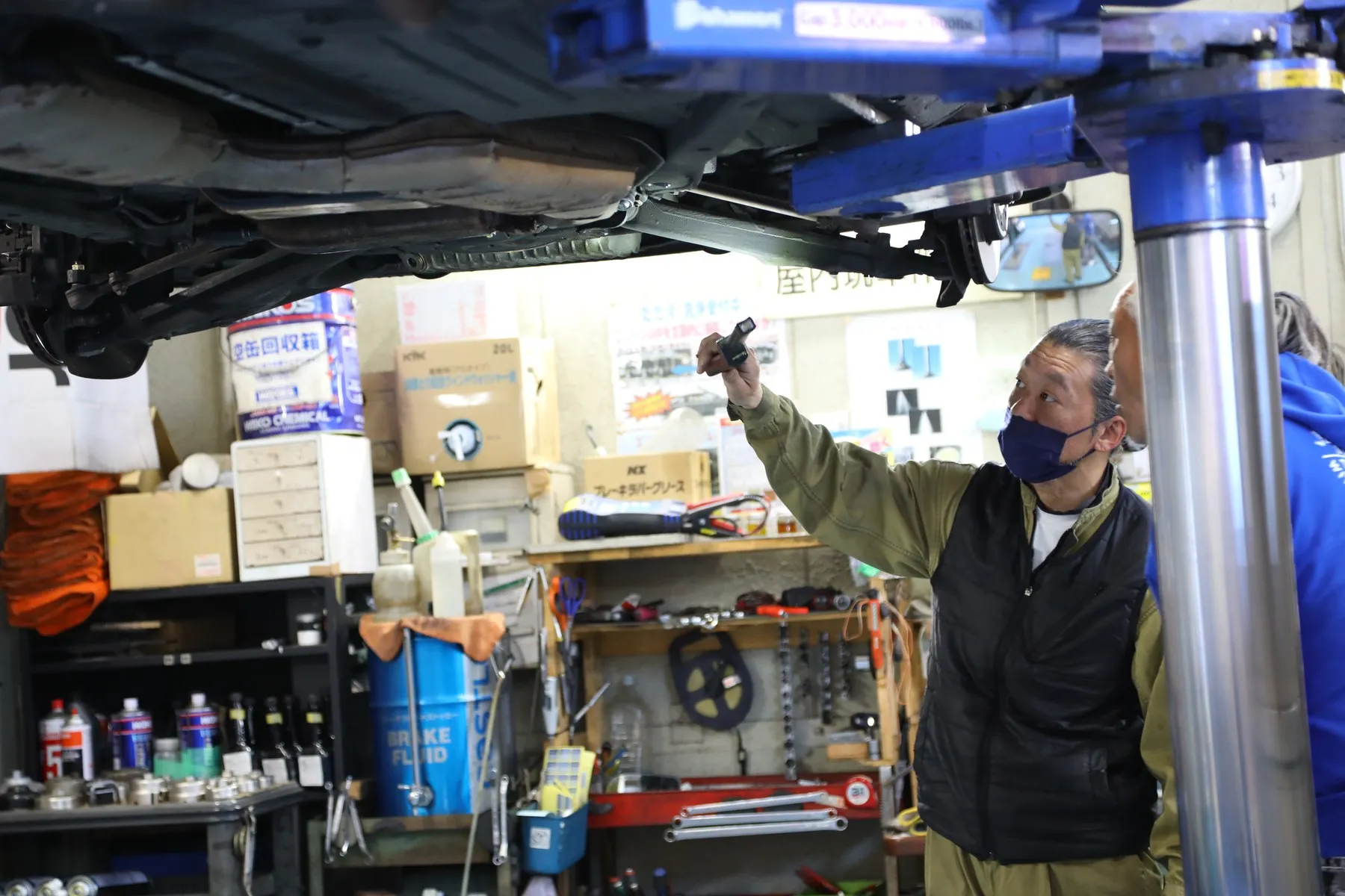 リフトアップした車両を点検する整備士